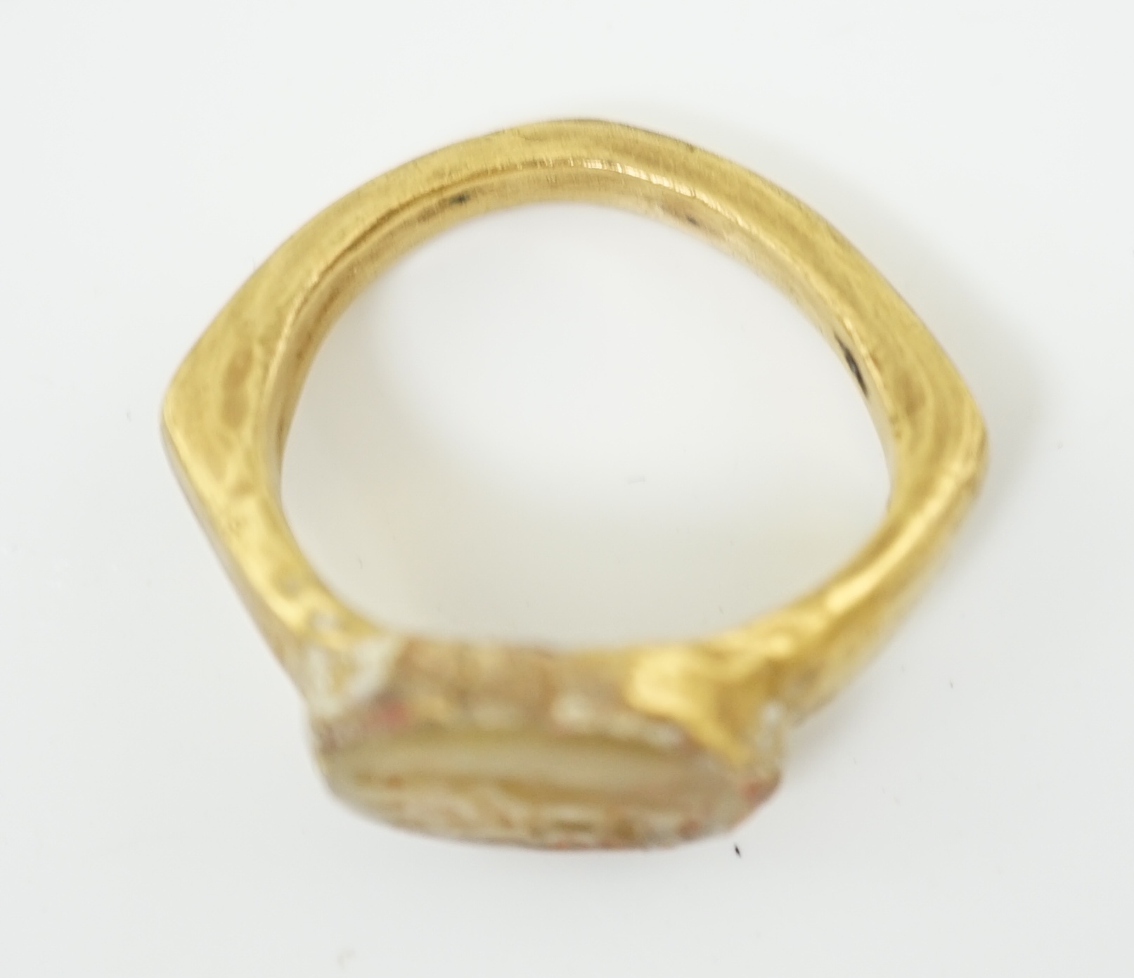 A Roman gold and hardstone intaglio military finger ring, carved with Saturn beside a pedestal